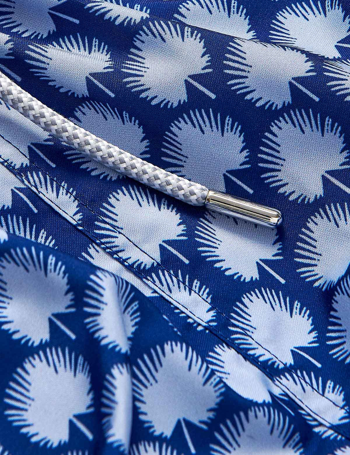 Patterned fabric of Men's Palm Fans Staniel Swim Shorts featuring a deep blue and sky blue tropical palm fans design with a white drawstring.