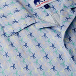 Close-up view of Star Dancer Arawak mens Linen Shirt featuring a pastel pink, limoncello, cay green, and deep blue sea star motif on a soothing ocean blue background.