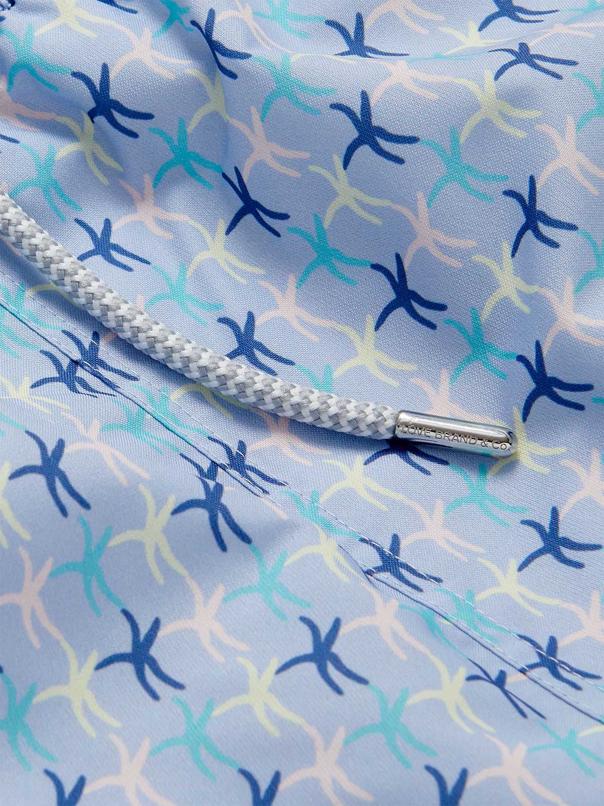 Close-up of the sea star pattern on the Men's Star Dancer Staniel Swim Shorts, showcasing pastel pink, zesty limoncello, fresh cay green, and deep ocean blue hues with a braided drawstring.