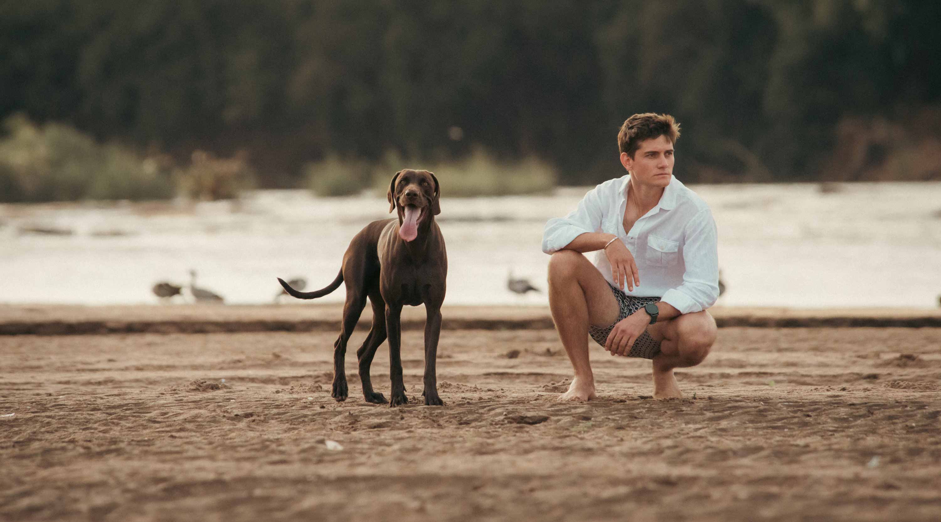 Taru Carr-Hartley wearing LOVE BRAND & Co. Men's White Andros Hemp Shirt and Bee Propelled Staniel mens swim shorts with his dog Dingo.