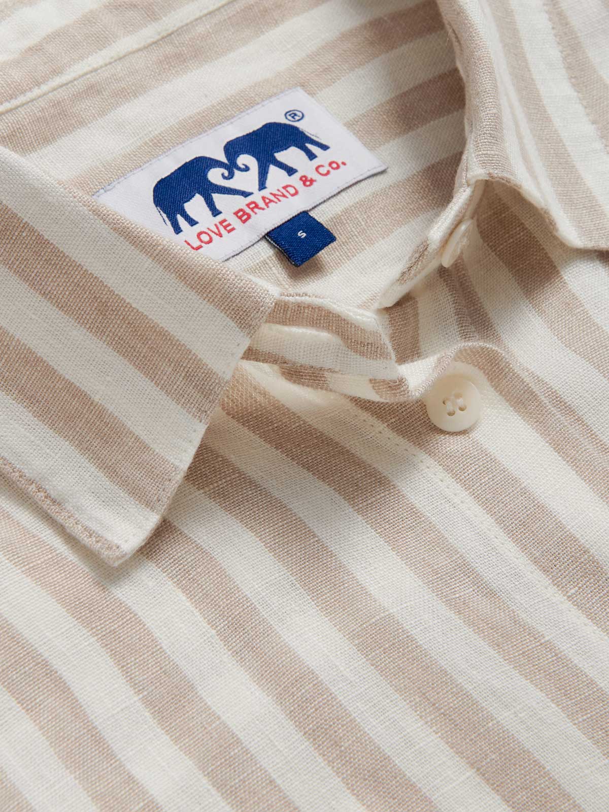 Close-up view of Womens Coconut Stripe Inagua Linen Shirt. Long-sleeved button-up 100% linen shirt with front pocket. Brown and white striped patterned all over.