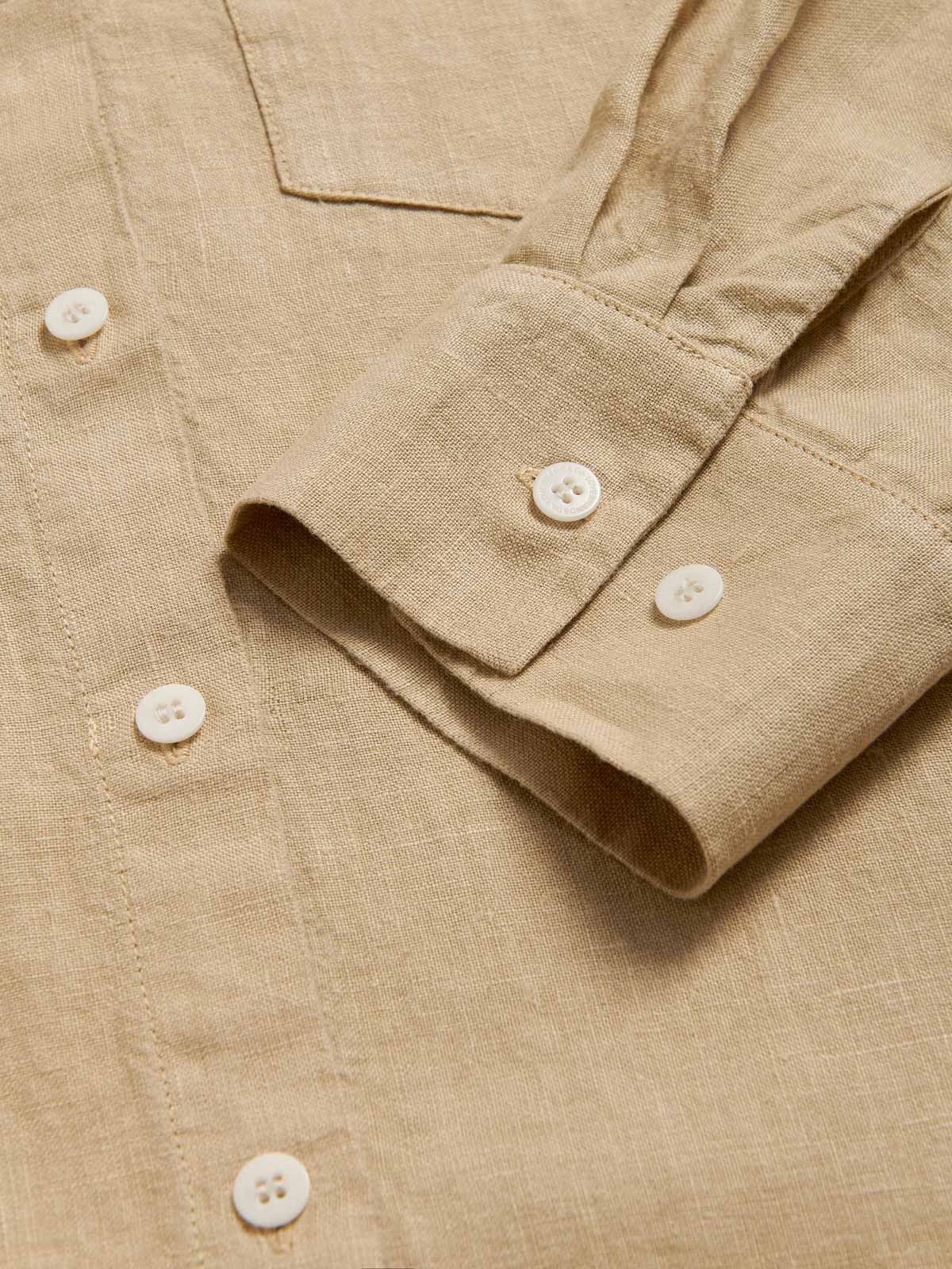 Beige midaxi linen shirt dress for women with long sleeves and a front pocket. Close-up view of cuff and linen fabric.