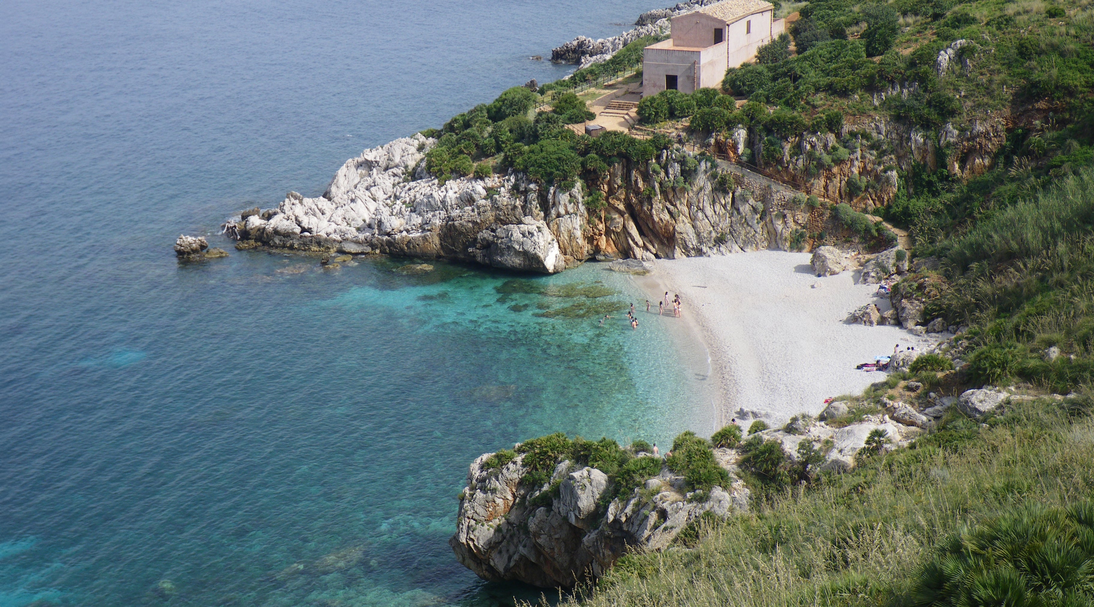 Coastal scene with a small beach and rocky cliffs at Zingaro Nature Reserve