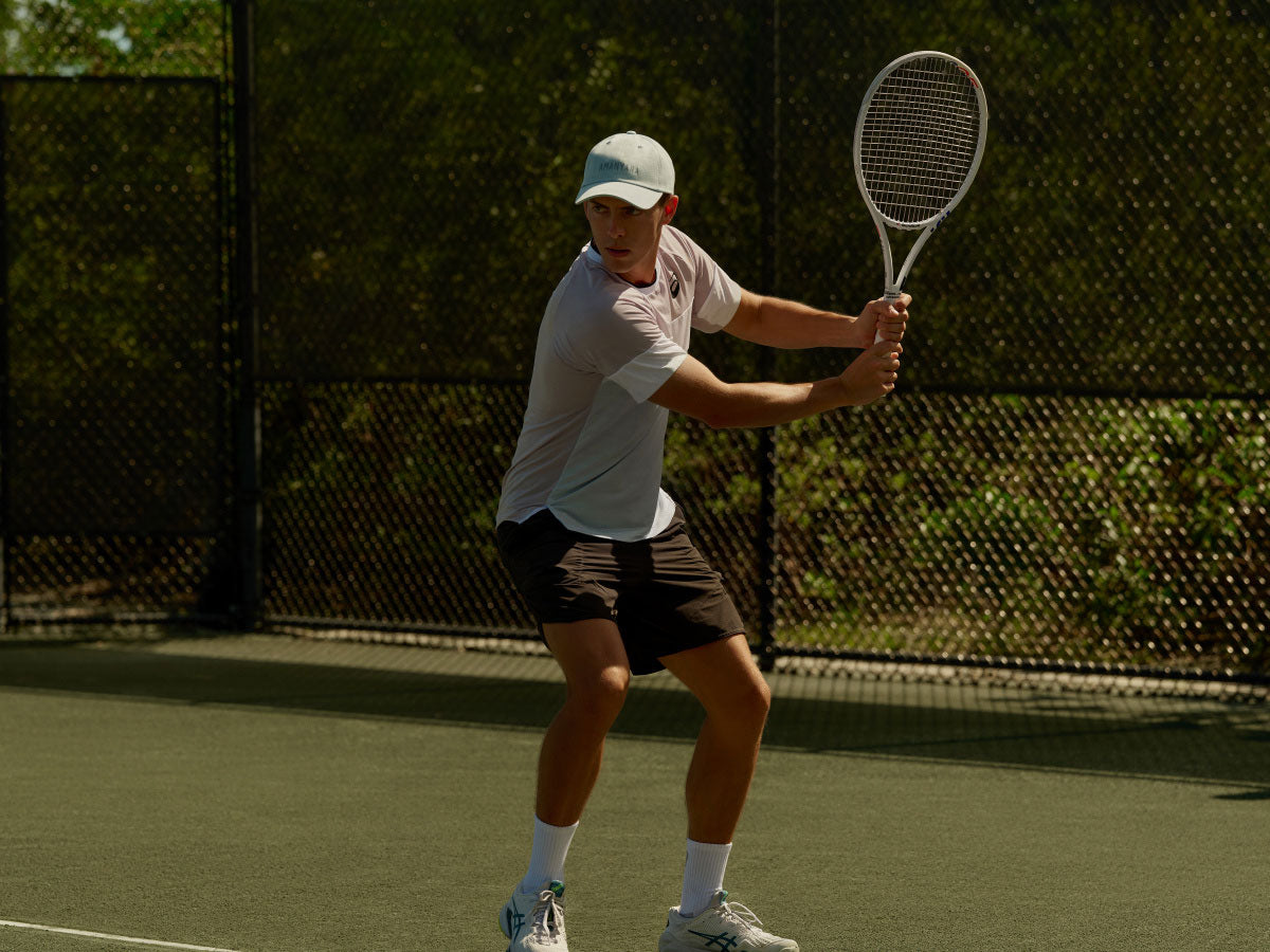 Person playing tennis on a court with a racket at Amanyara