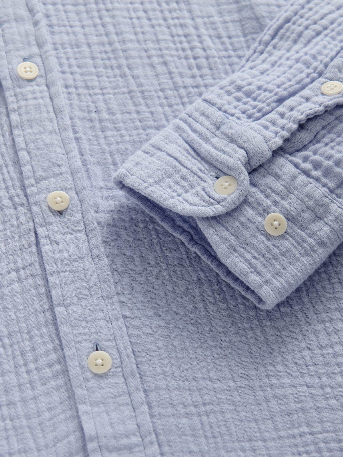 Close-up of a light blue textured shirt with buttons