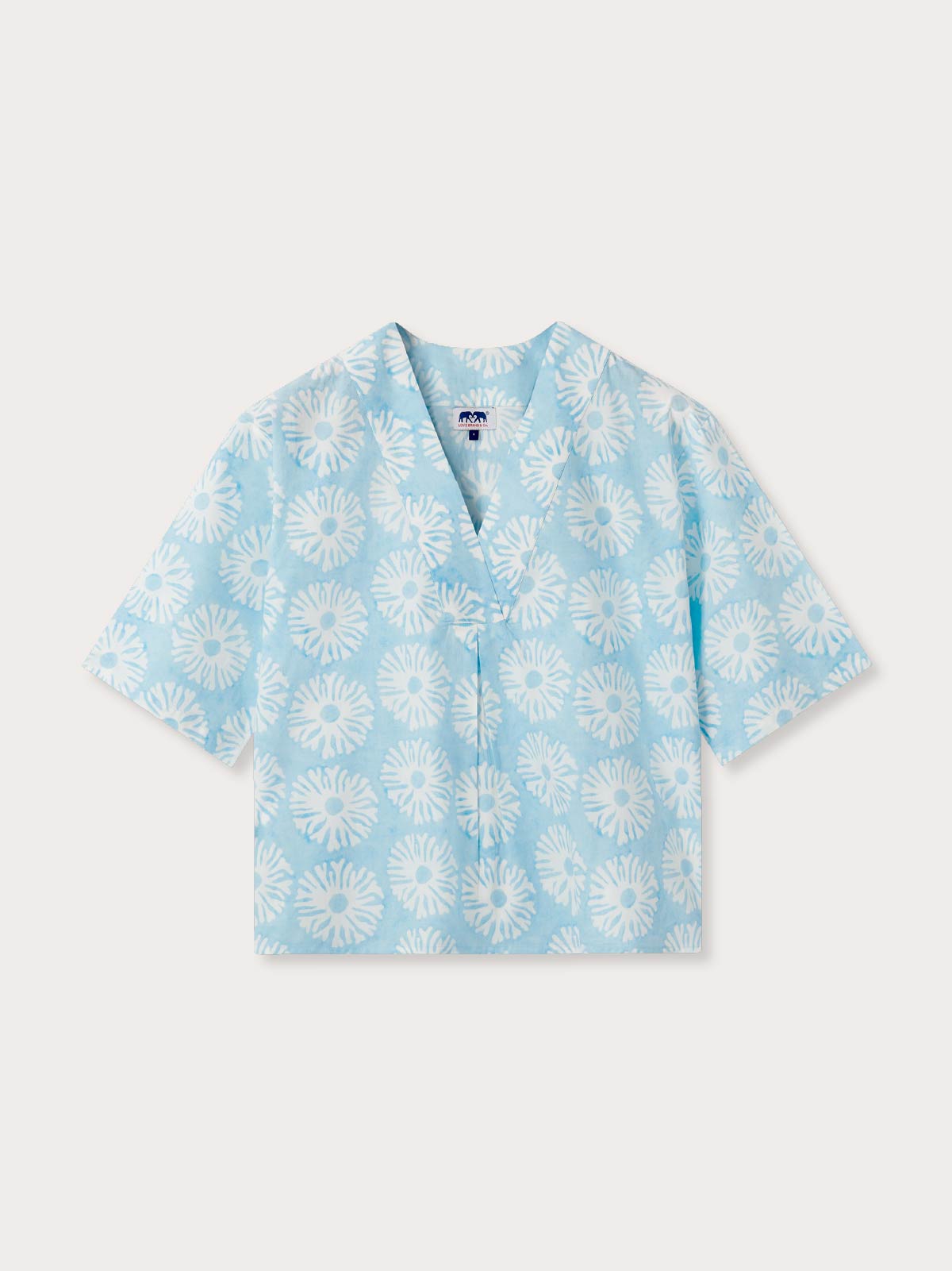 Light blue blouse with white coral pattern on a light grey background.