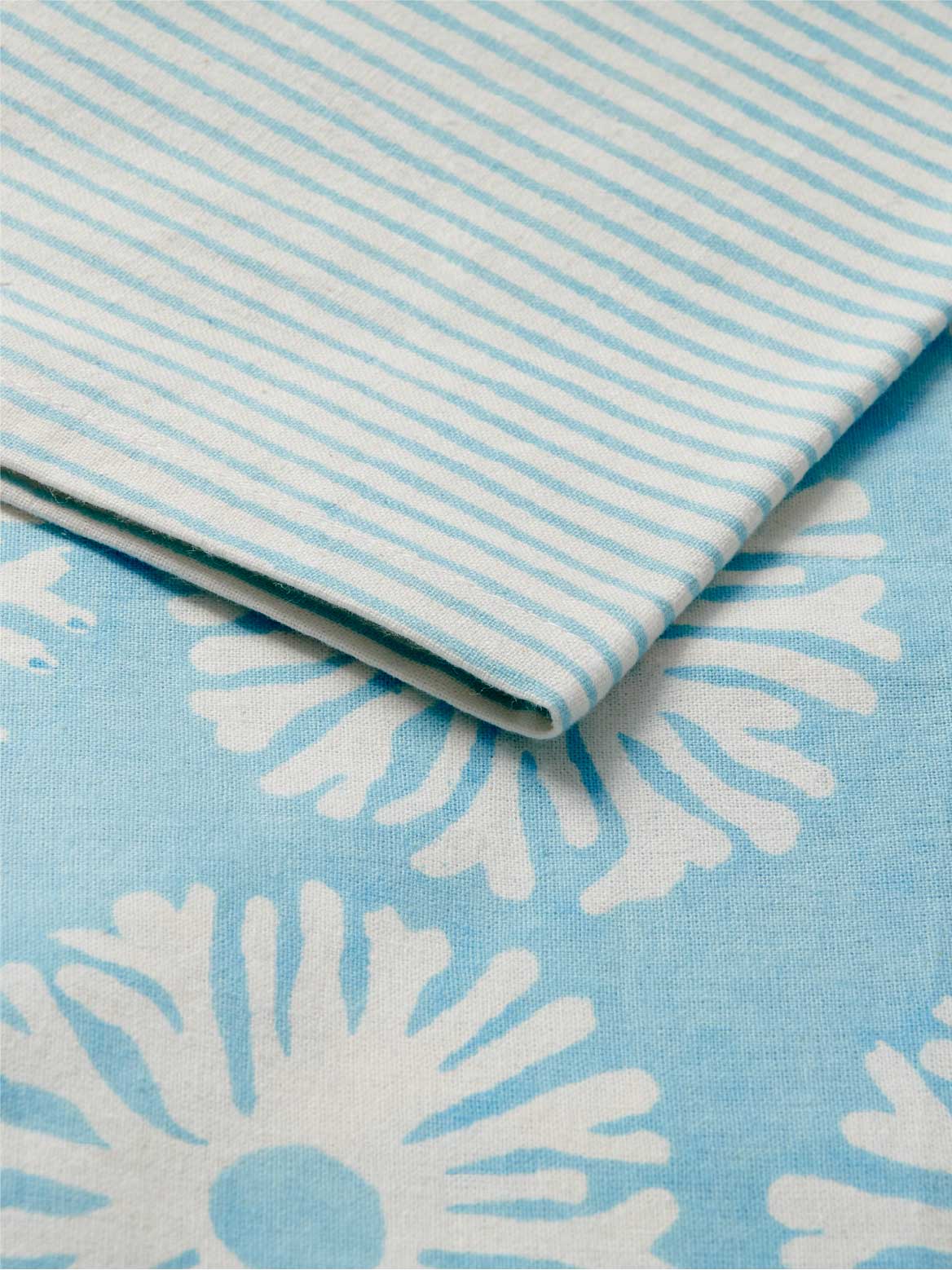 Close-up of blue and white striped tablecloth with a floral pattern.