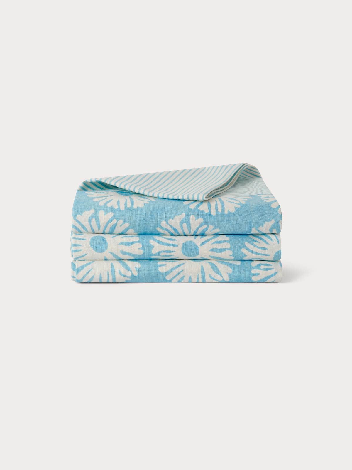 Folded blue cotton tablecloth with blue and white coral pattern.