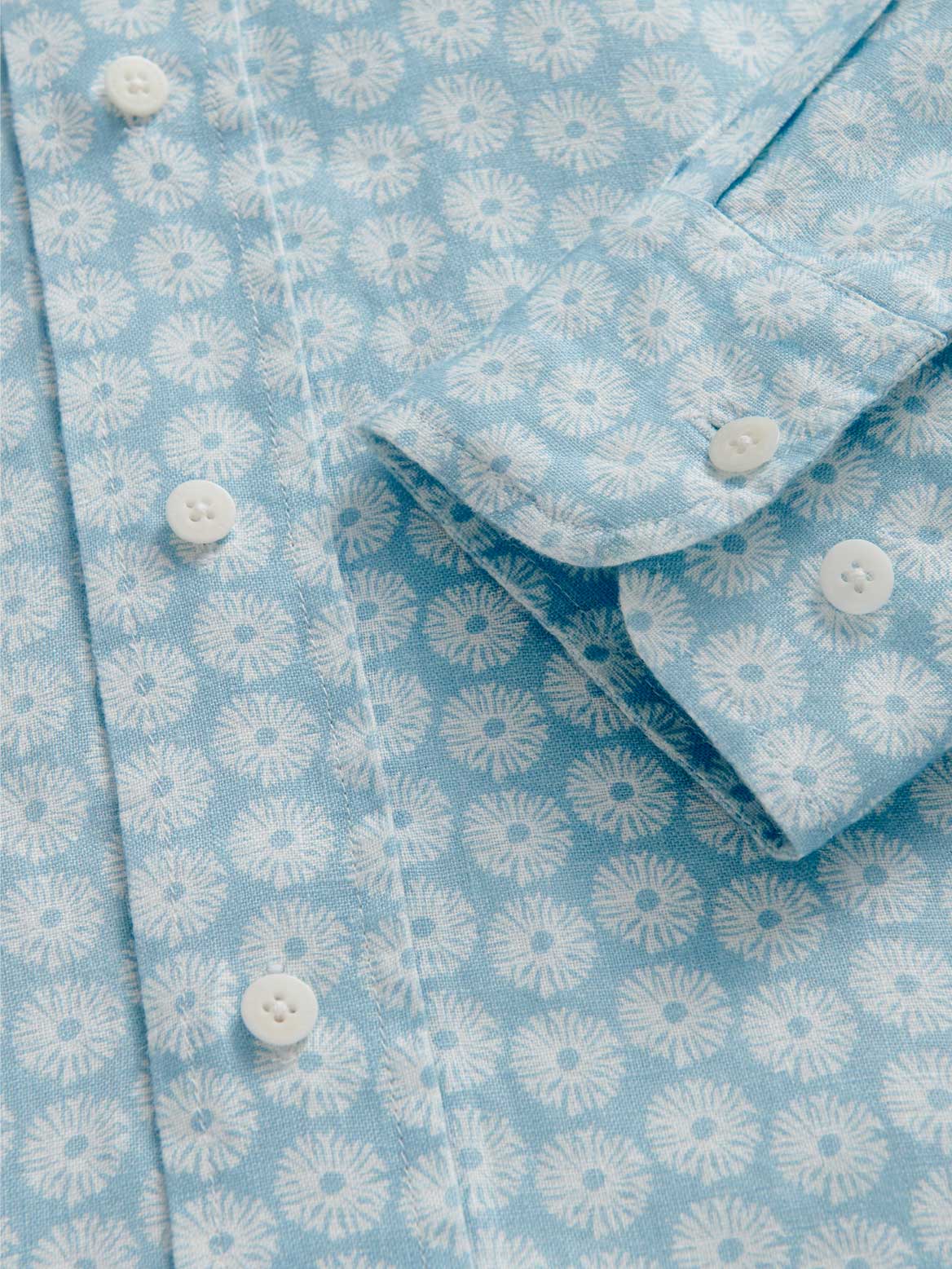 Close-up of a blue shirt dress with white coral pattern and buttons.