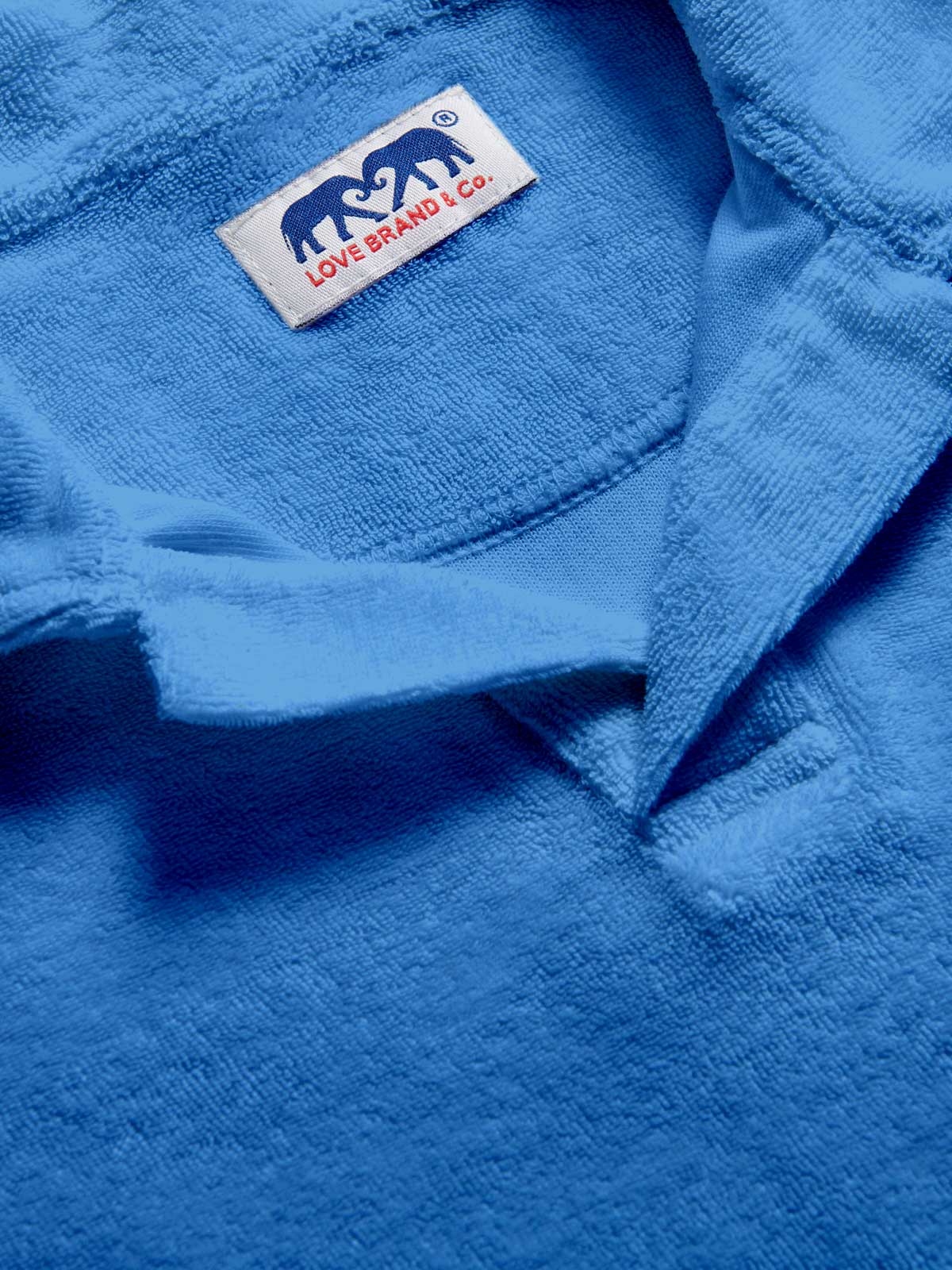 Close-up of a blue terry towelling fabric with a visible love brand label featuring an elephant design.
