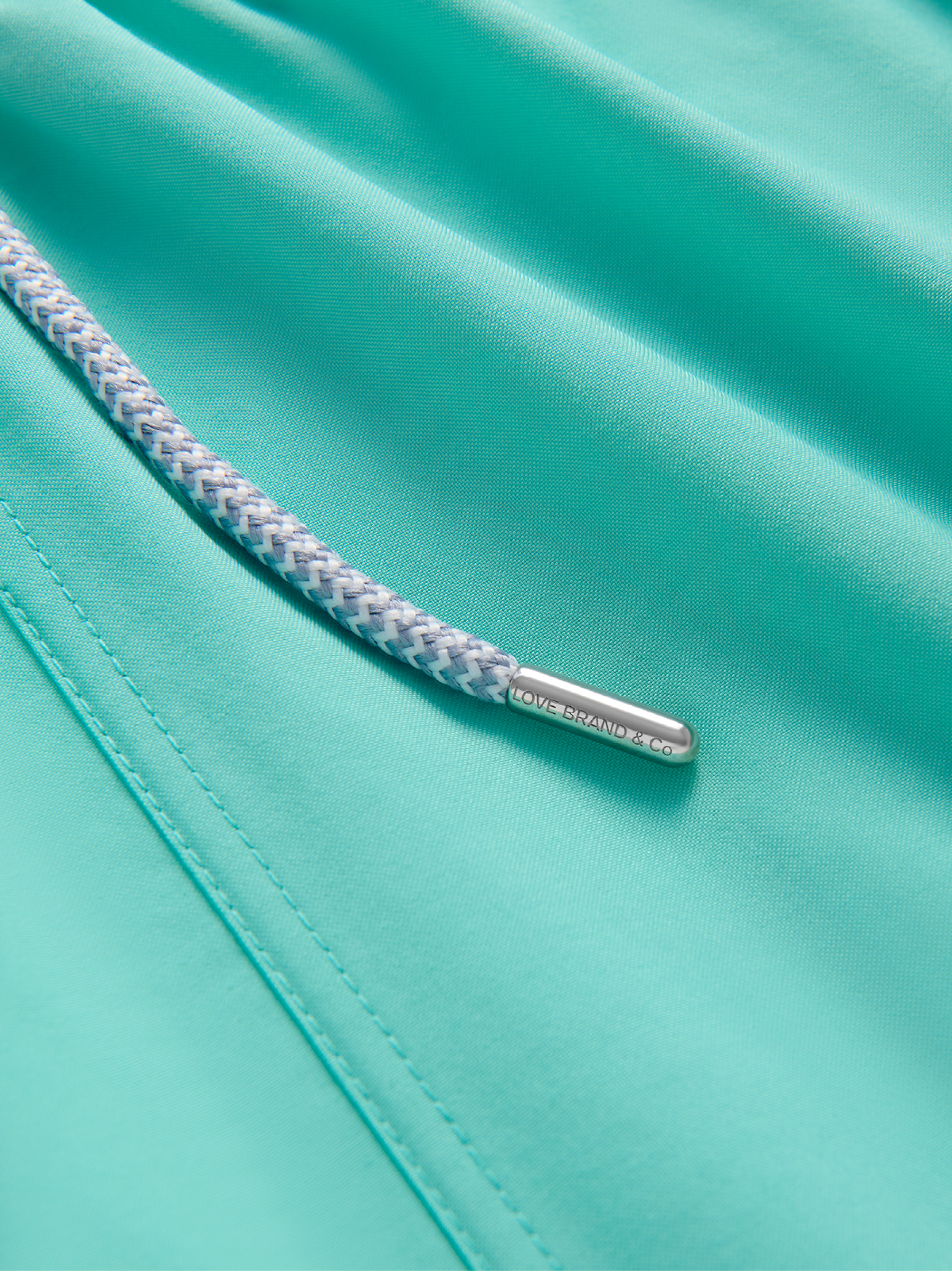 Close-up of a teal swim shorts fabric with a drawstring