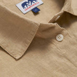 Close-up view of beige midaxi linen shirt dress with long sleeves and a front pocket.