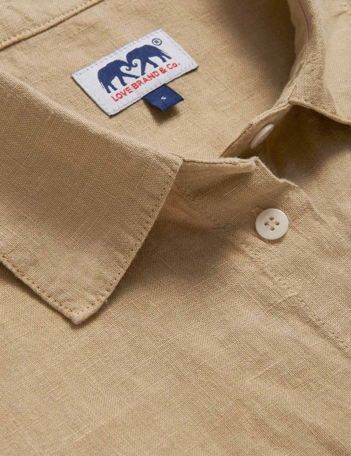 Close-up view of beige midaxi linen shirt dress with long sleeves and a front pocket.