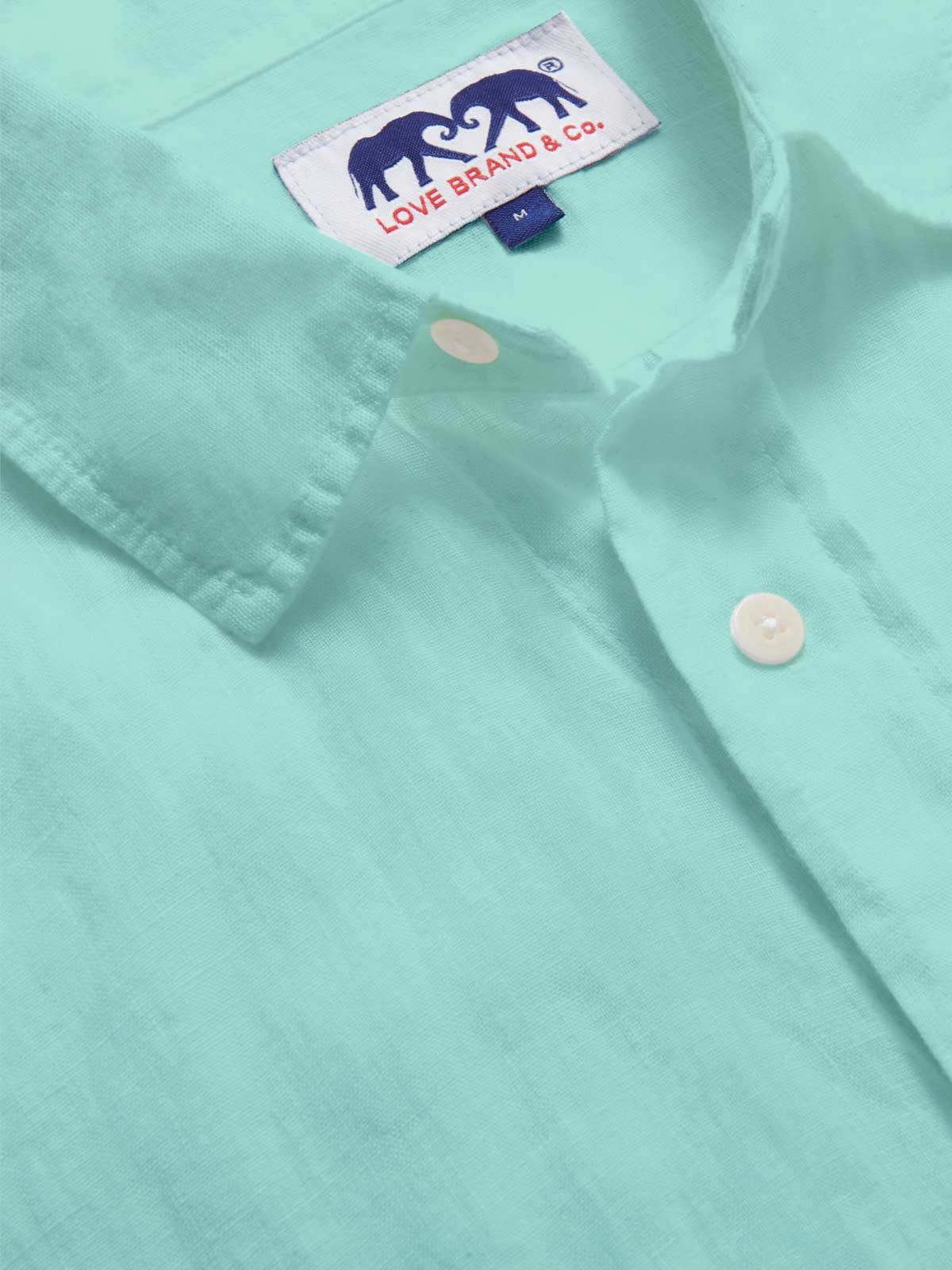 Close-up view of the Men's Cay Green Abaco Linen Shirt fabric, showcasing the vibrant green hue and fine texture of the 100% linen material.