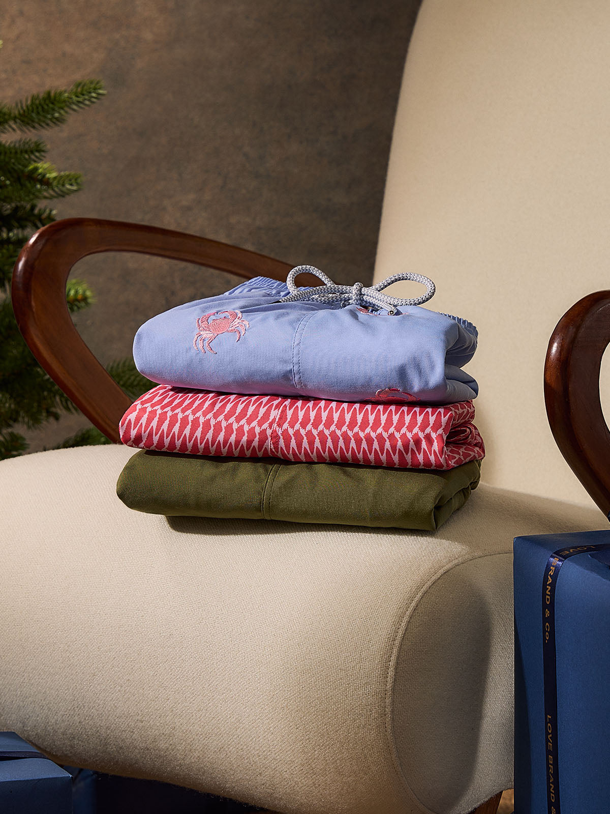 Stack of folded swim shorts on a chair with a neutral background