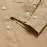 Close-up view of Womens Coconut Inagua Linen Shirt. Long-sleeved brown linen shirt with button-up design and front pocket. Crafted from 100% linen.