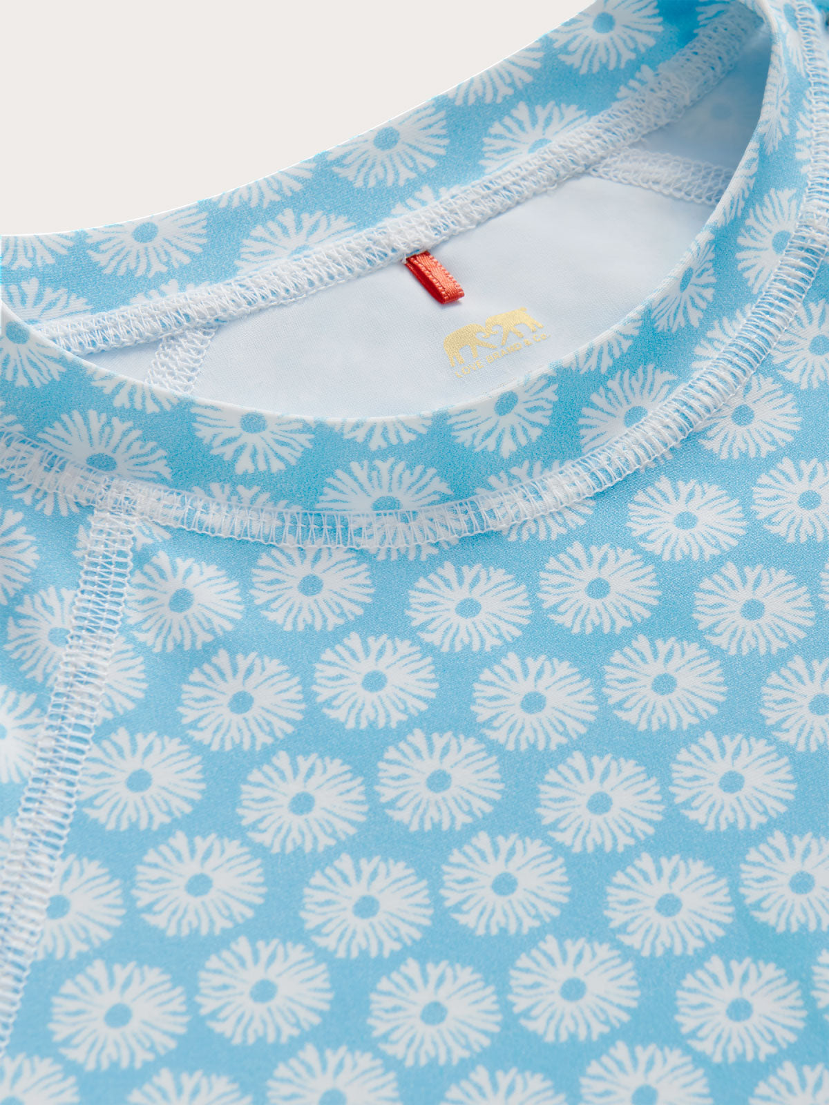 Close-up of a blue fabric with white floral pattern and red tag.