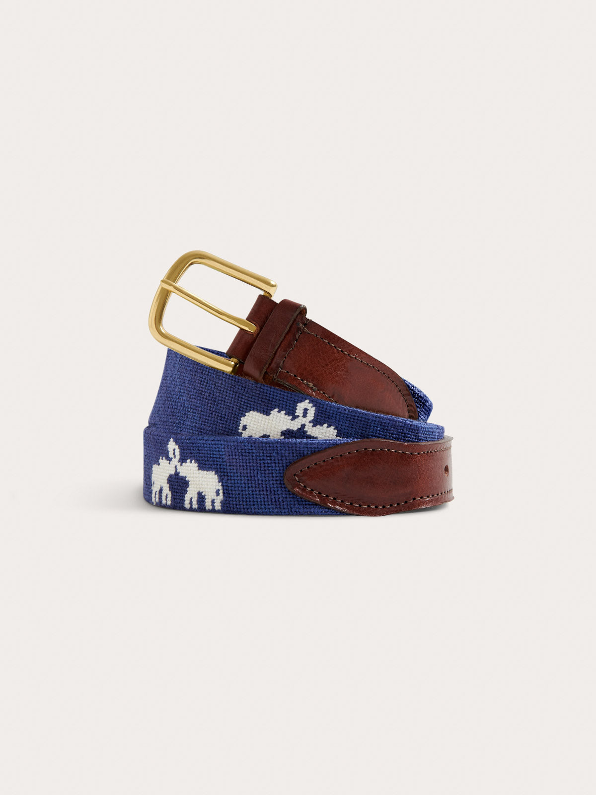 A navy blue woven canvas belt with white embroidered elephant motifs and brown leather trim, featuring a silver metal buckle, shown on a light off-white background.