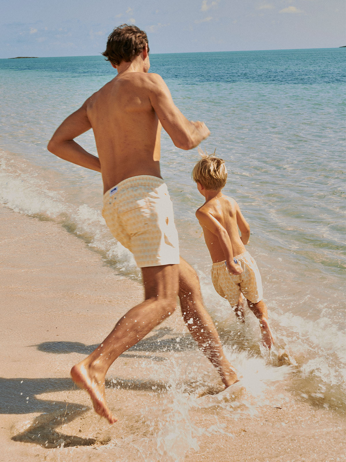 man runs with child wearing father son matching swim shorts
