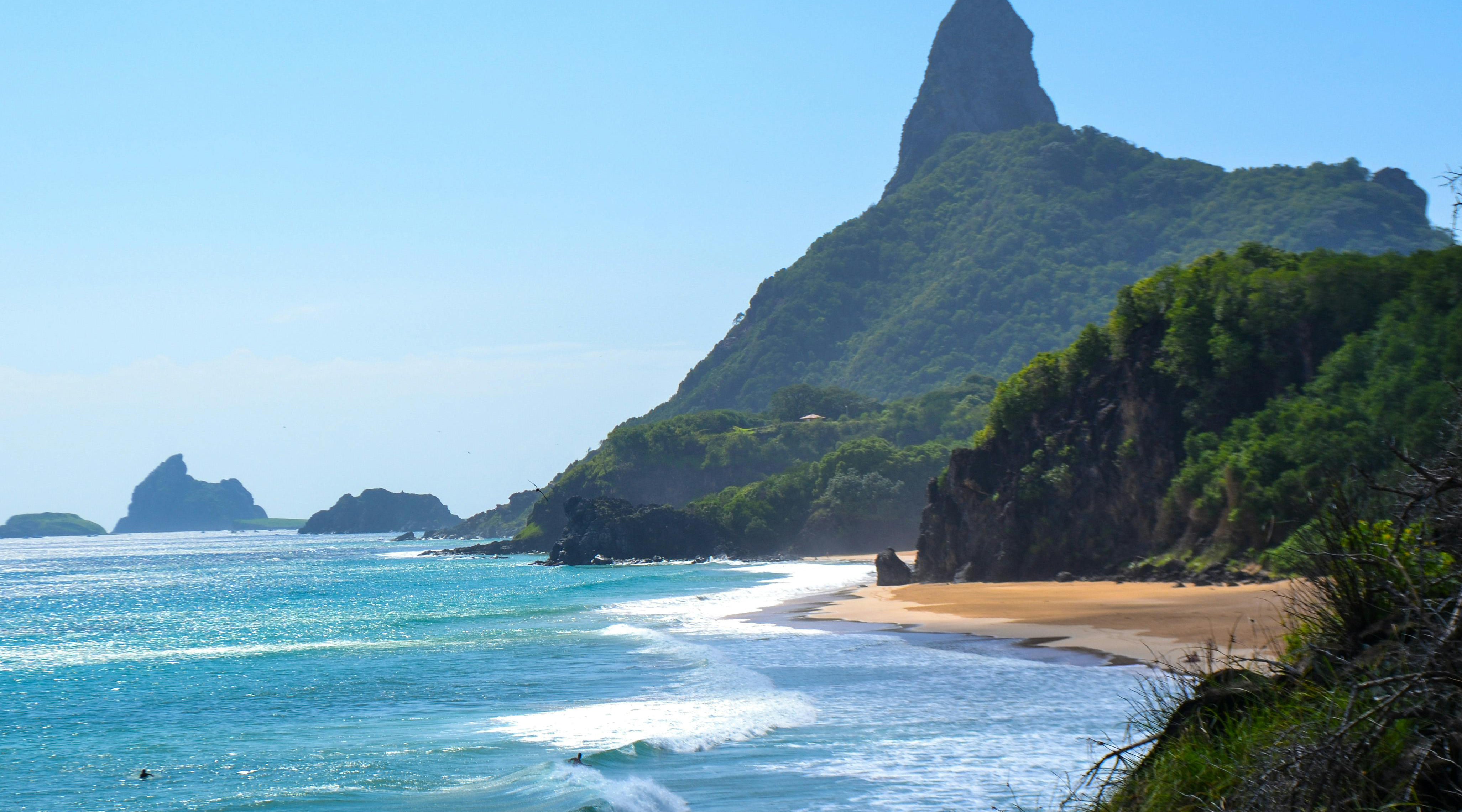 Beach with a mountain in the background under a clear blue sky