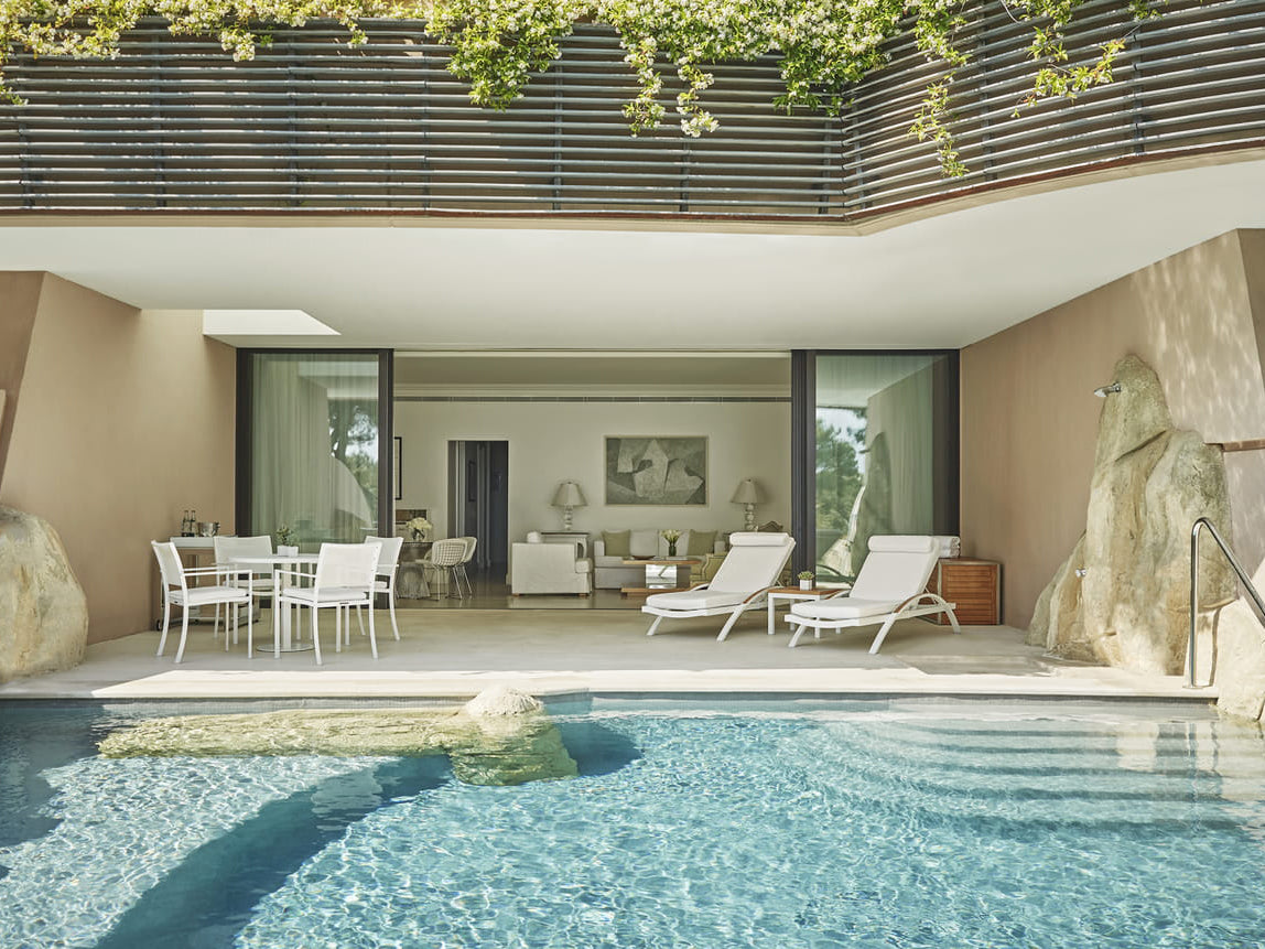 Modern room with a pool area featuring lounge chairs and a dining table.