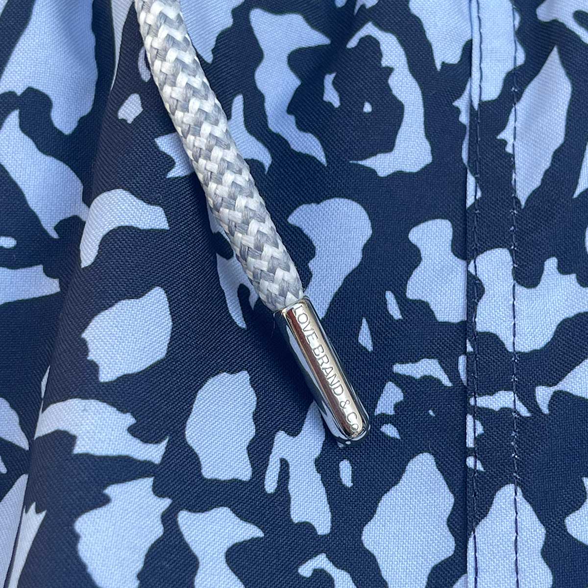 Close-up view of Boys Island Camo Staniel Swim Shorts, showcasing the blue and black Greek island camo pattern and a detailed drawstring with "OliverandRose" branding.