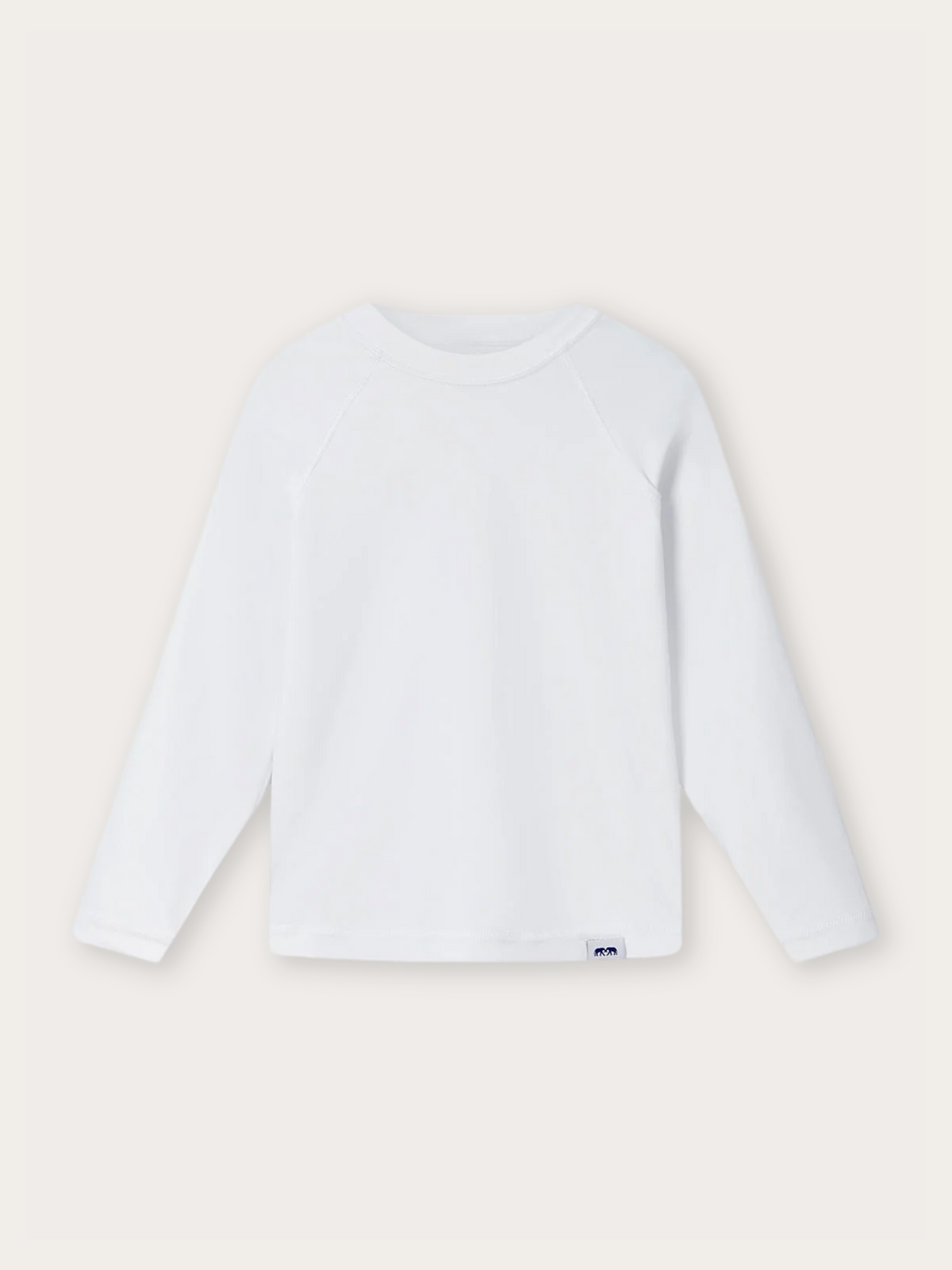 A white long-sleeve rash vest with a small blue and white logo tag near the bottom hem, displayed flat against a light beige background.