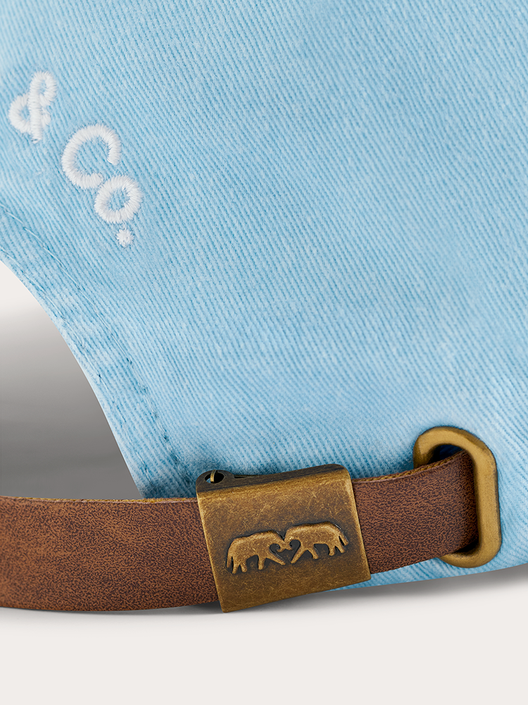 Close-up of a blue denim fabric with a brown leather strap and gold buckle featuring a logo.