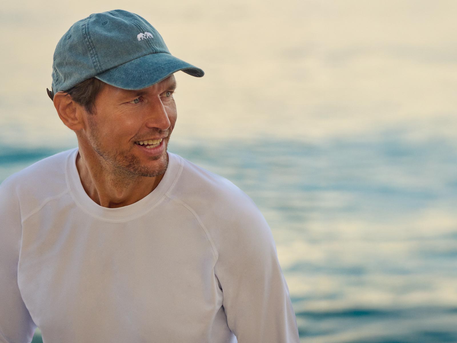 Man wearing a blue cap and white shirt standing by the water
