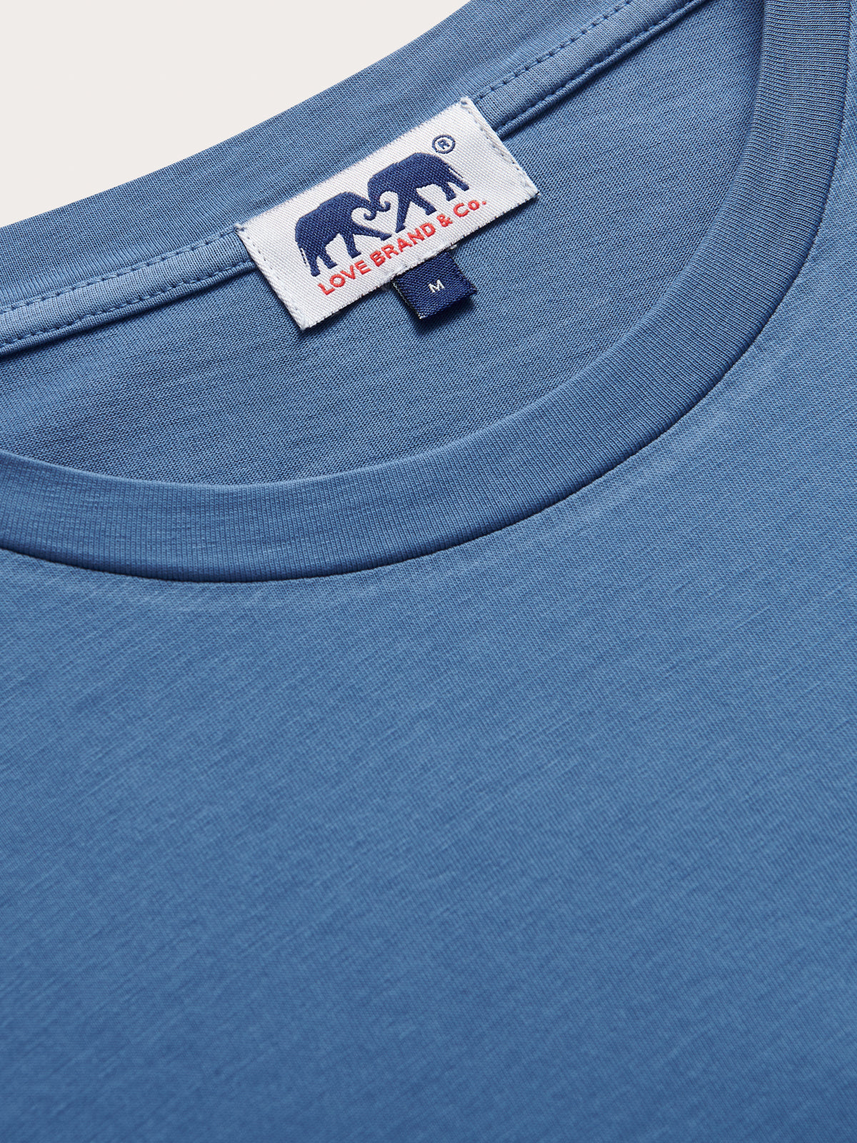 Close-up of a blue t-shirt with a brand label on the collar.