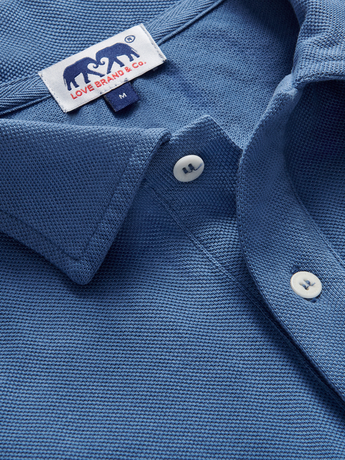 Close-up of a blue shirt with a brand label on the collar.
