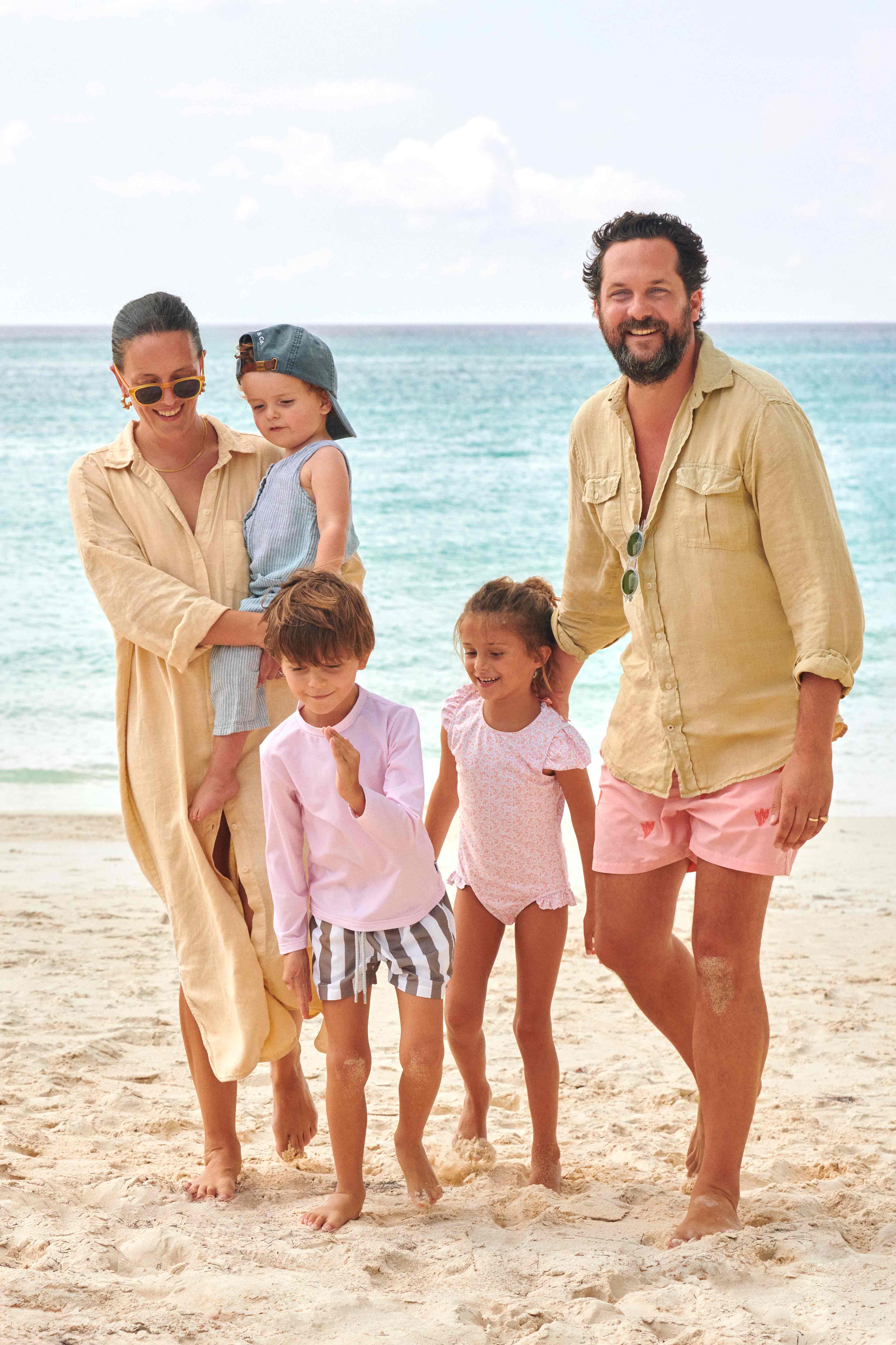 Family of five standing on a beach with ocean in the background