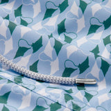 Close-up of the patterned fabric detail on the "Men's Which Way to the Tropics Staniel Swim Shorts," featuring an emerald and white manta ray design, with a white drawstring.