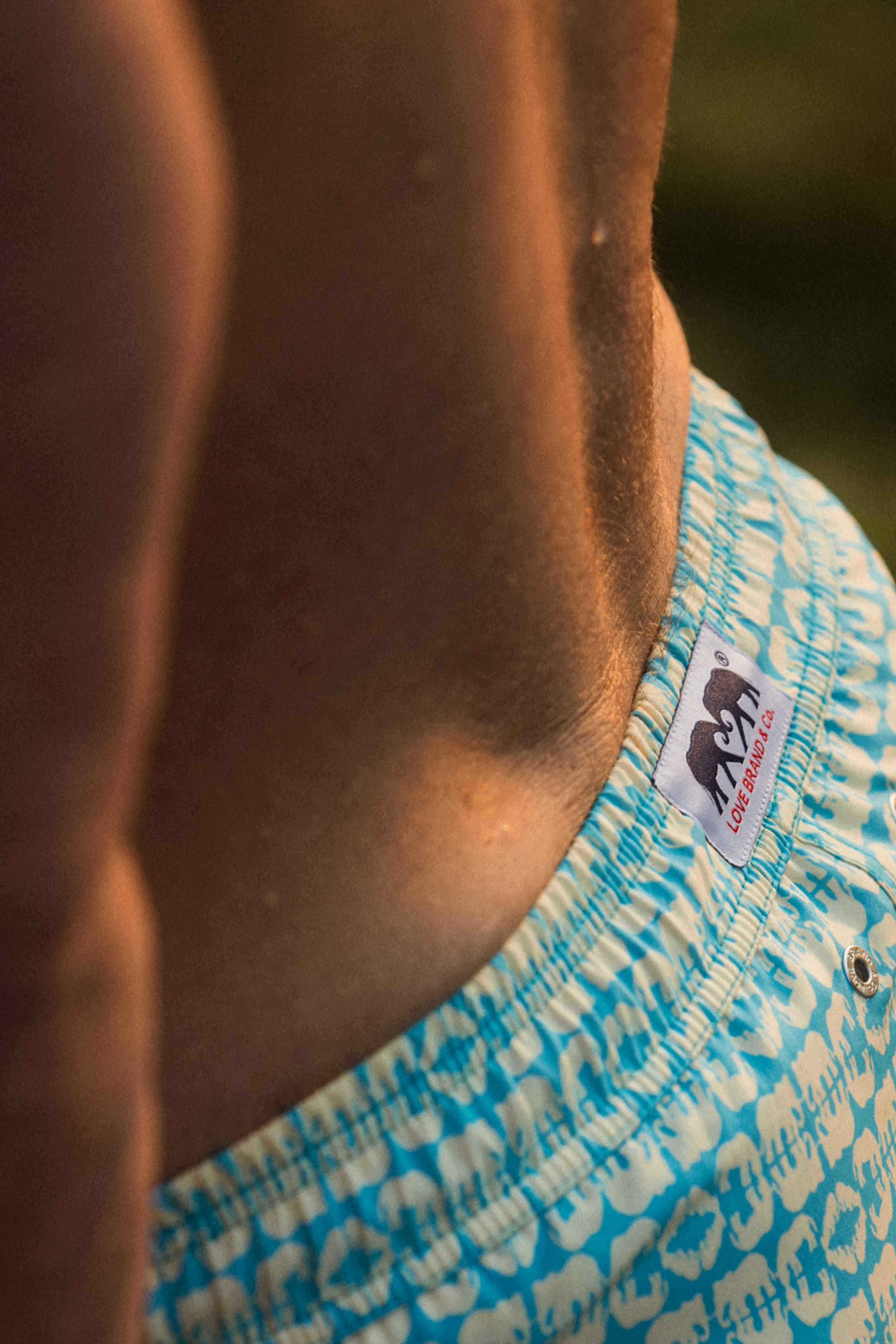 Close-up of a person wearing blue patterned swim shorts with a visible brand logo.