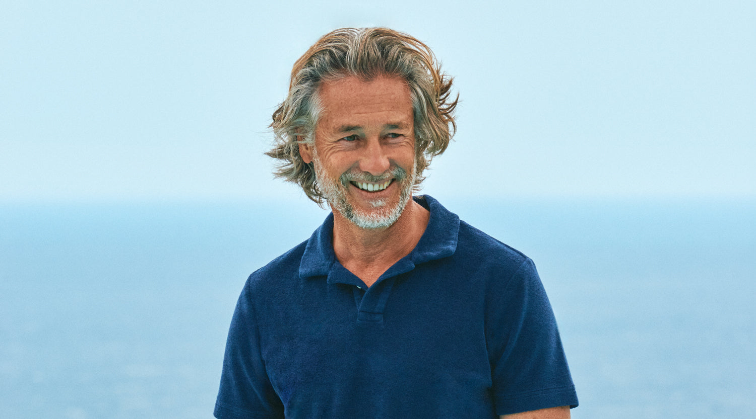 Man wearing a blue terry polo shirt against a light blue sky