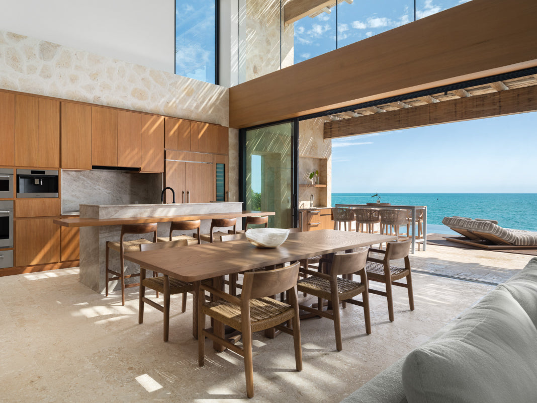Modern kitchen at The Strand with wooden dining table and chairs, overlooking a scenic ocean view.