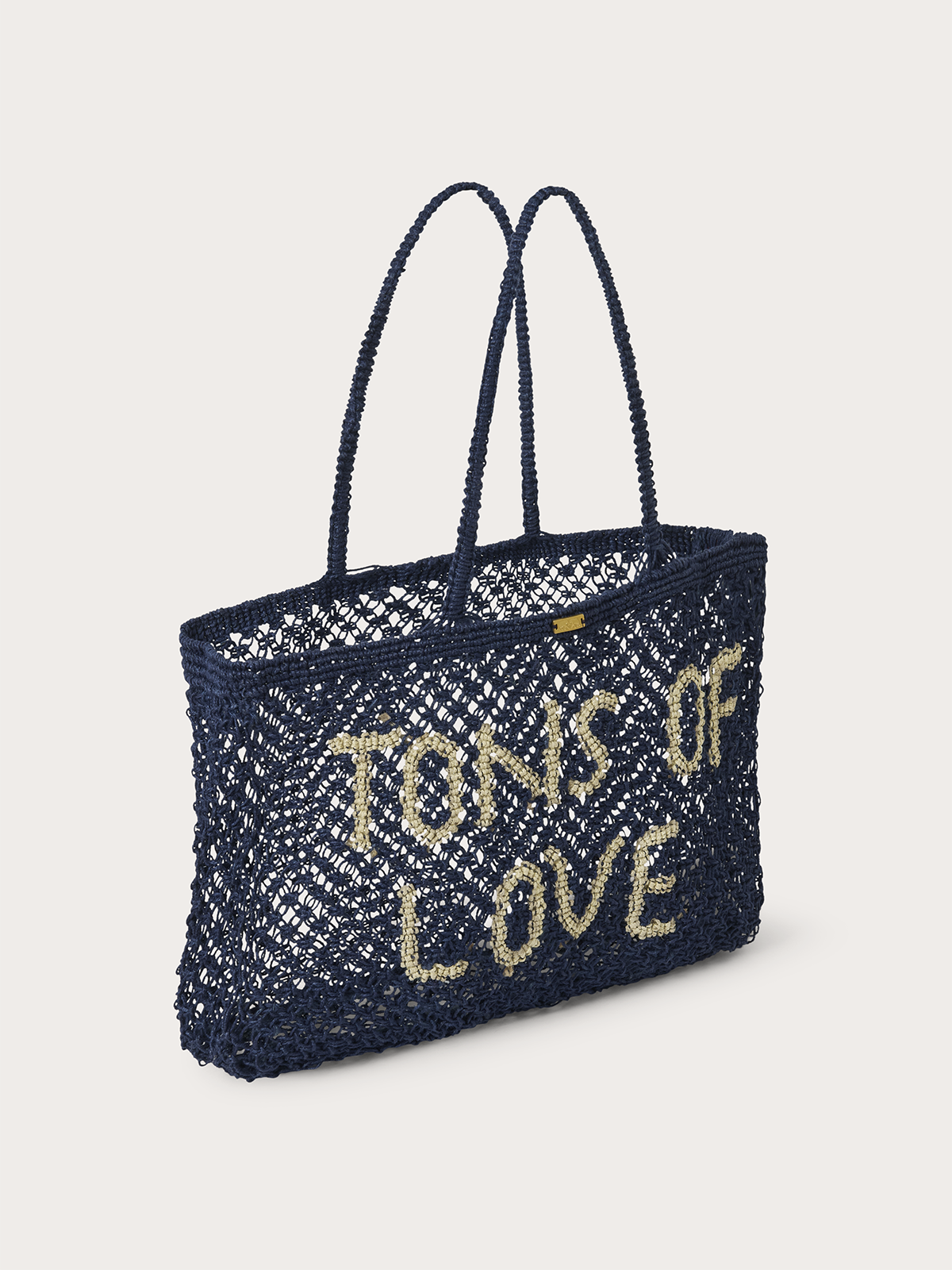 A navy blue crocheted tote bag with 'TONS OF LOVE' written in beige yarn, set against a solid light grey background.