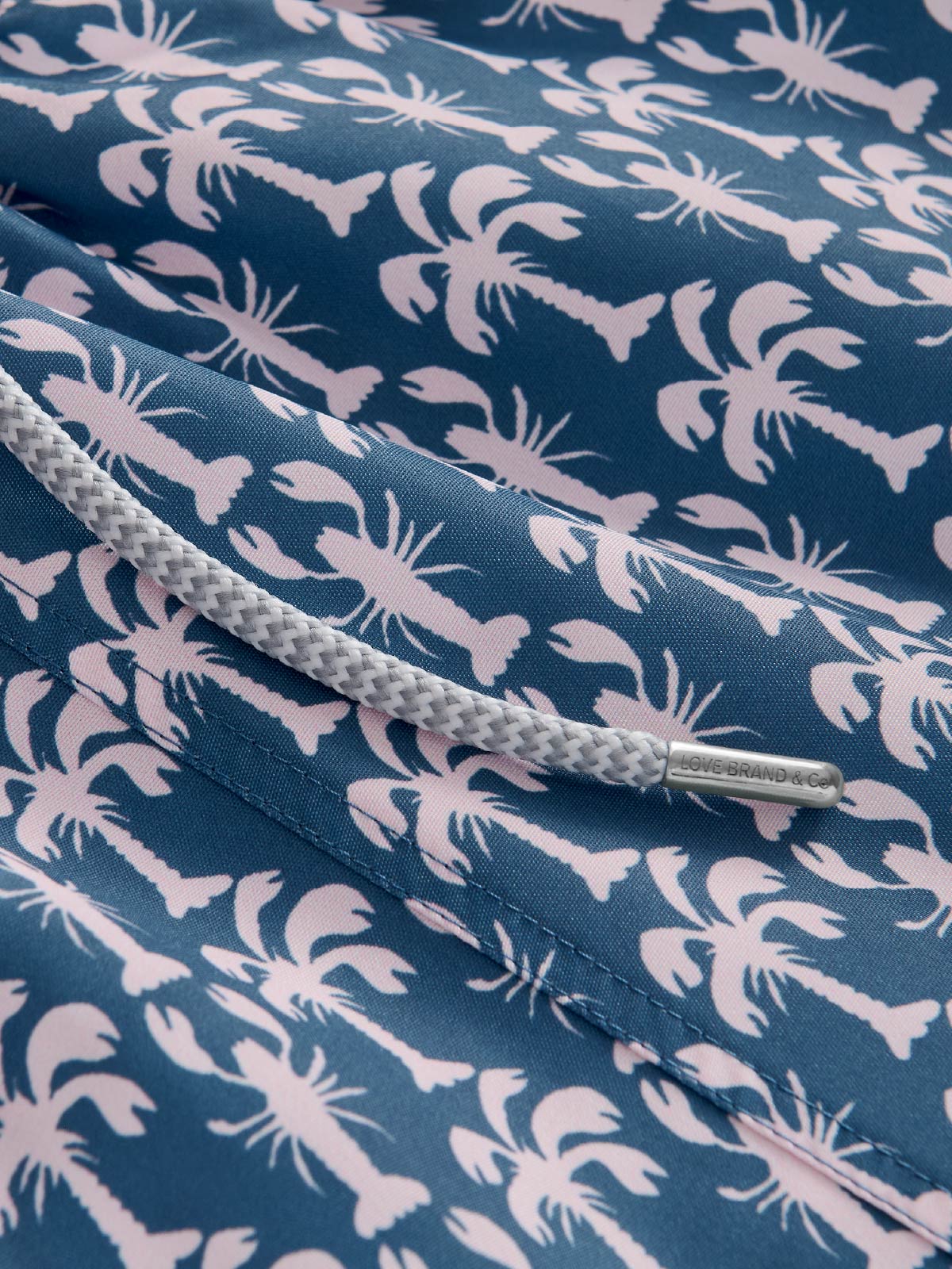 close-up of lobster swim shorts with blue and pink geometric print.