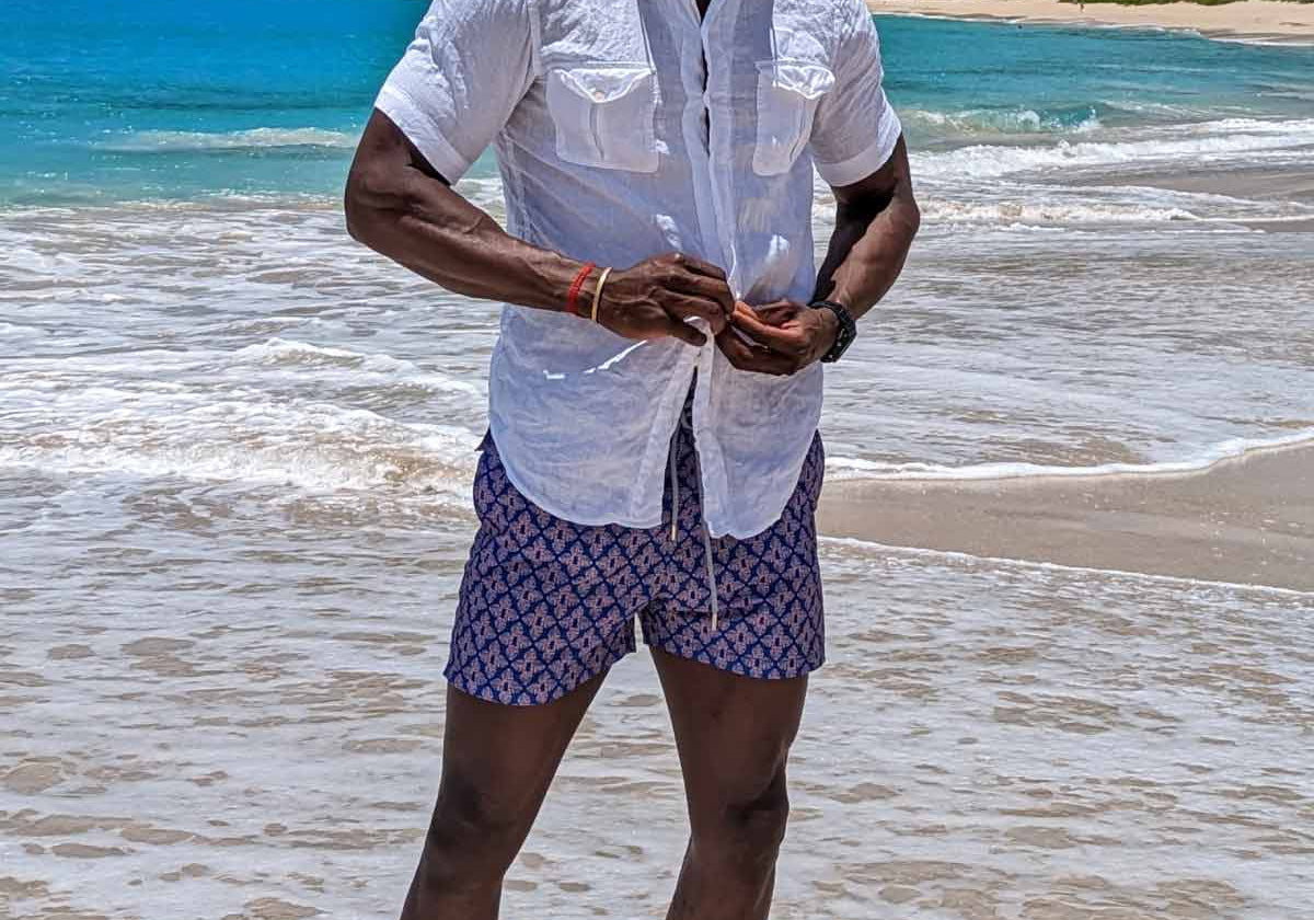 man wears white linen shirt and swim shorts by luxury swimwear brands uk