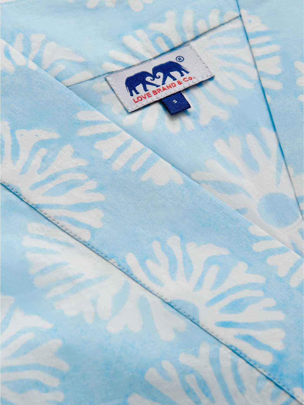Light blue fabric with white coral patterns and a visible brand label.