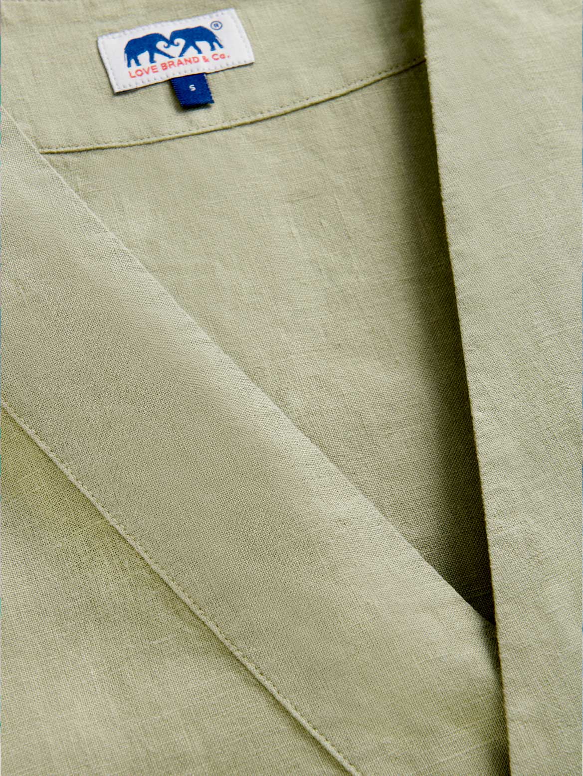 Close-up of a green v-neck relaxed fit top with a brand label.