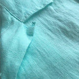 Close-up of Cay Green Arawak mens Linen Shirt showing its soft, breathable fabric texture in a light tropical green color inspired by the Bahamian Cays.