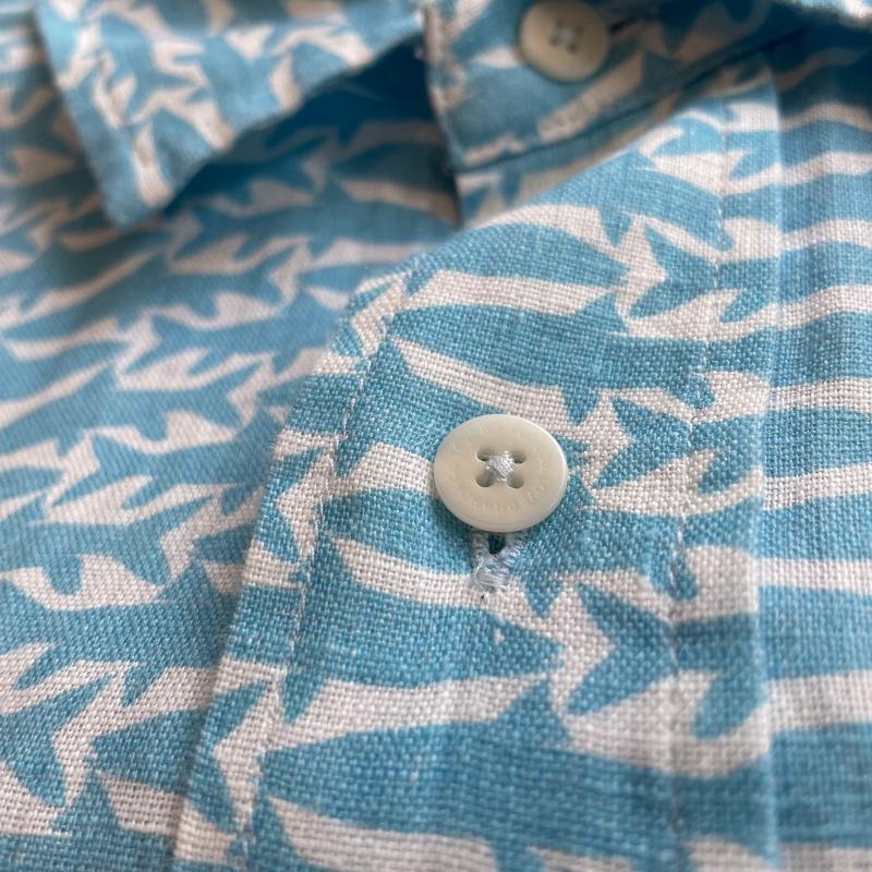 Close-up of Fish Fauna Abaco mens Linen Shirt in blue, featuring a pattern inspired by the endangered Golden Mahseer, with white buttons.