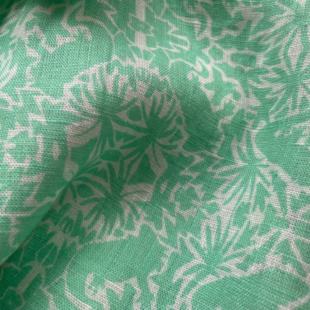 Green and white patterned fabric of Men's Island Iguana Manjack Linen Shirt featuring palm leaf and iguana design.