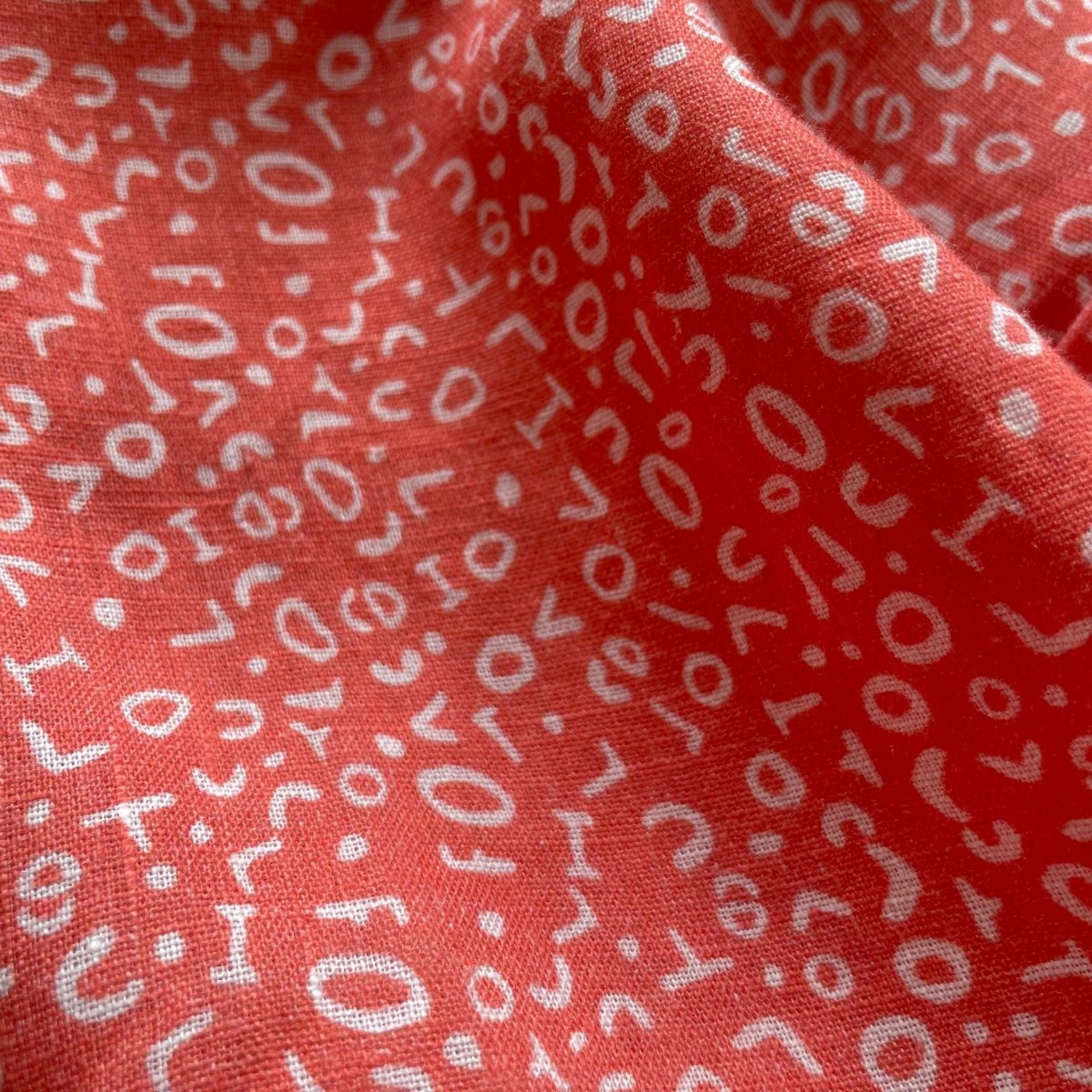 Close-up of coral linen fabric with intricate white patterns inspired by Staniel Cay Spotted Eagle Rays from the Men's Code Ray Manjack Linen Shirt.