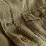 Close-up of the Men's Olive Green Andros Hemp Shirt showcasing the durable 100% organic hemp fabric, pleated double chest pocket, and signature corozo nut buttons.