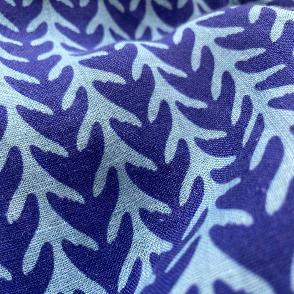 Close-up of the fabric pattern on the Men's Whale Tale Abaco Linen Shirt, showcasing a design that resembles dark blue whale tails or seagrass against a light blue background.