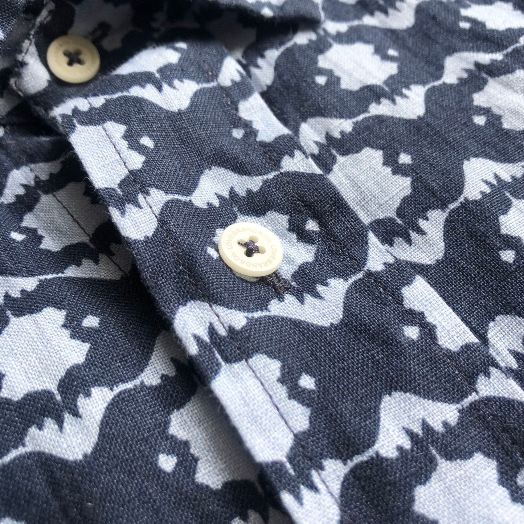 Close-up view of Men's Rhino Rhythm Manjack Linen Shirt. Men's linen shirt featuring geometric rhino print with button-up design and short sleeves.