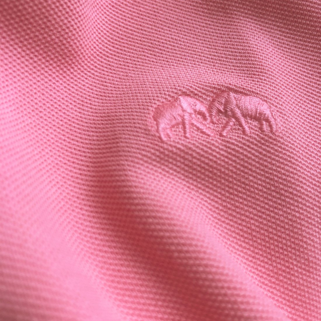 Close-up image of the fabric texture and embroidered logo on the Watermelon Pensacola mens Polo Shirt in bright pink color.